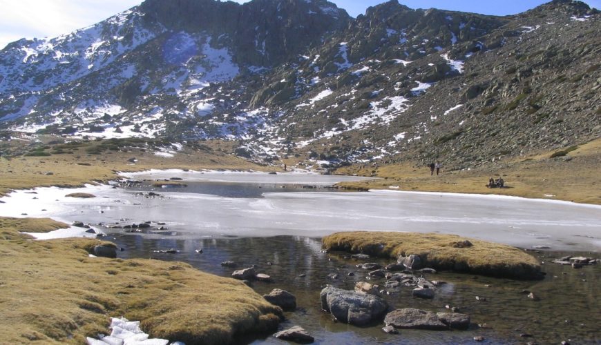 Laguna de los Pájaros parcialmente helada con el risco de los Claveles al fondo en Peñalara